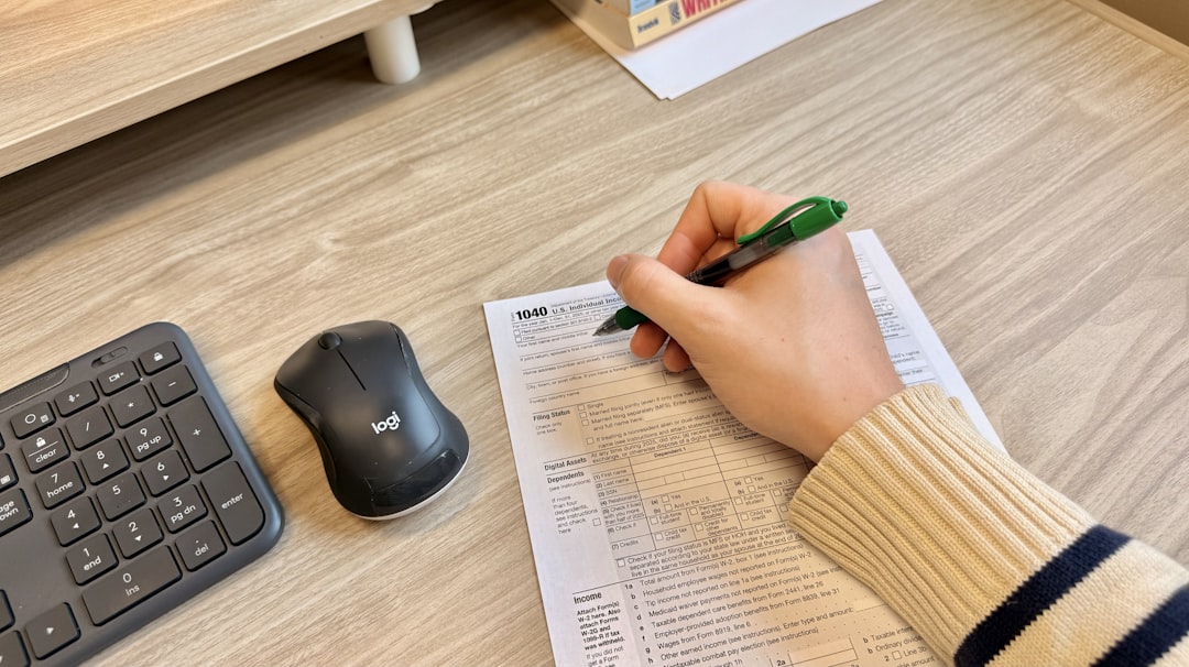 Hand writing on document next to keyboard and mouse